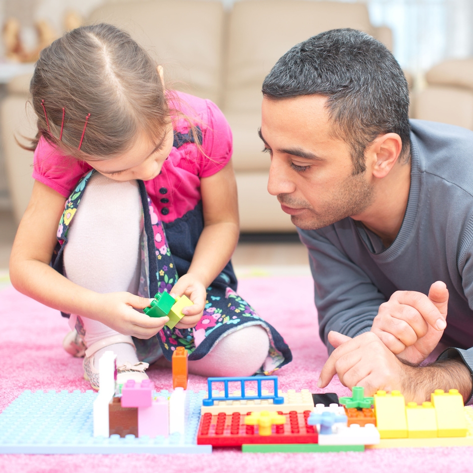 dad and daughter sitting on floor playing with blocks
