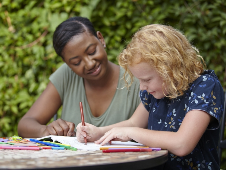 a woman helps a child with their drawings 