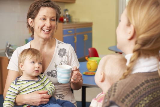 two mums with babies on knee having a chat