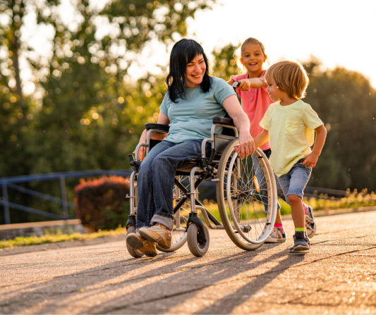 a mum in a wheelchair with two children out in the sunshine