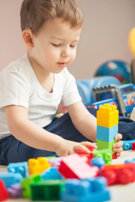 small boy playing with brightly coloured building blocks