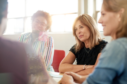 A small group of adults sitting around a table looking supportive